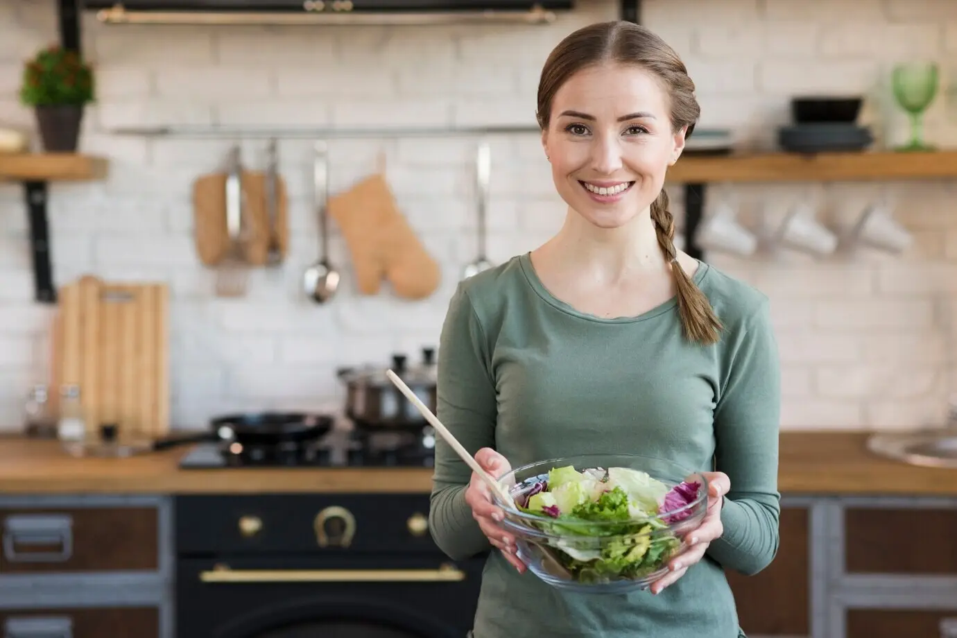 Portrait of a young woman displaying a freshly made salad.